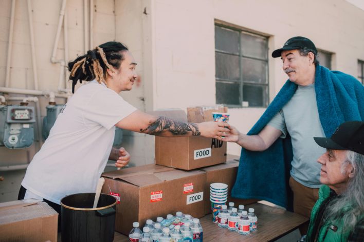 Volunteers distribute food and aid packages to those in need, fostering community support.